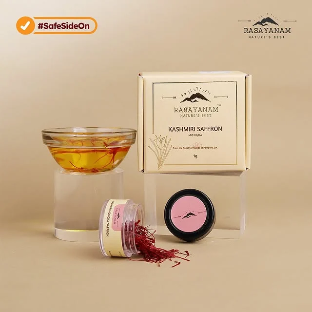 The saffron box, two jars, a small pink bowl and a glass of saffron water on a beige background.